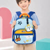 A smiling young boy wearing a light blue t-shirt and beige pants holds a blue and light blue school backpack with cartoon animal designs, a small matching pouch, and an orange top handle.